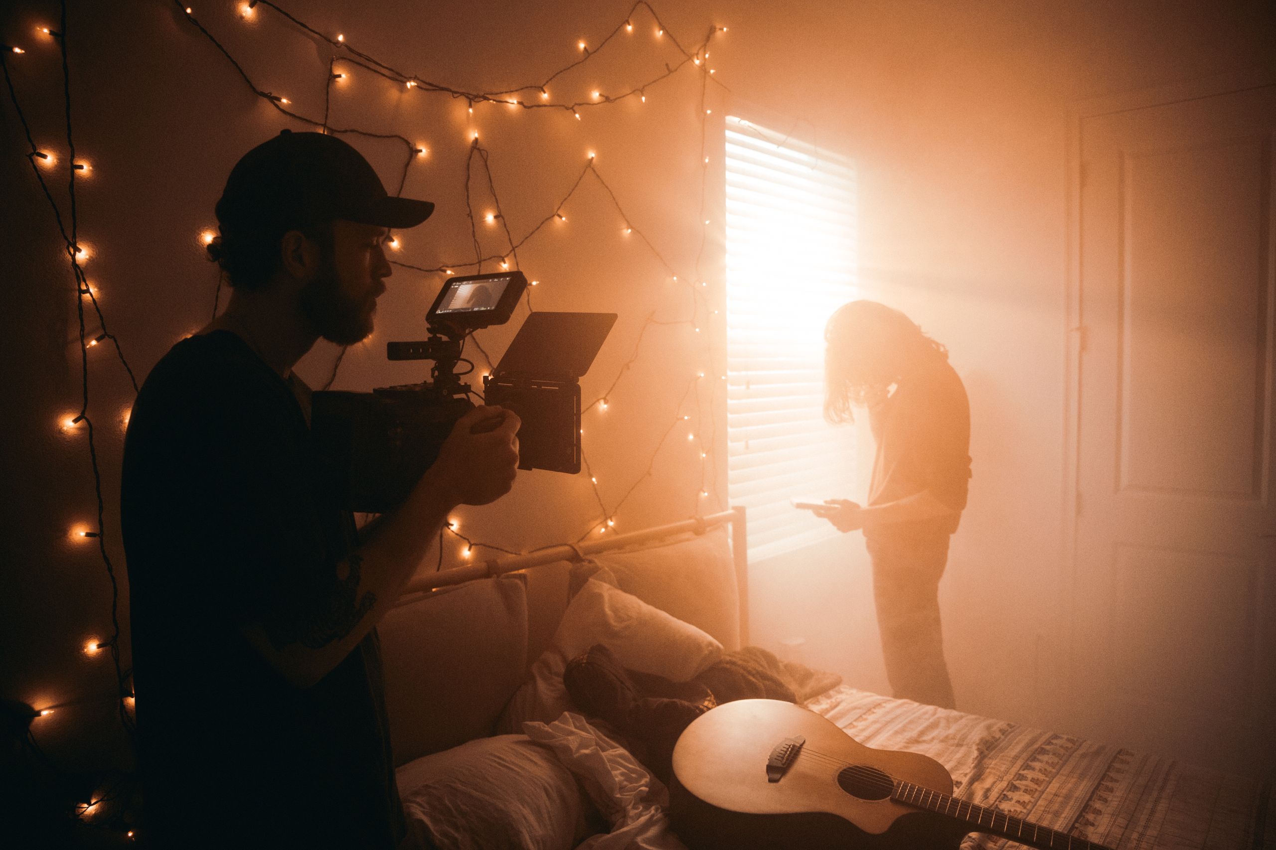 A filmmaker captures a scene in a dimly lit bedroom with string lights. - Breck Film | Eclipse Theater